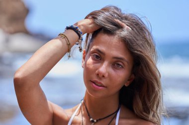 Sahilde doğal ışık altında mayolu, bronzlaşmış, heterokromisi olan güzel bir kadının yakın plan portresi.