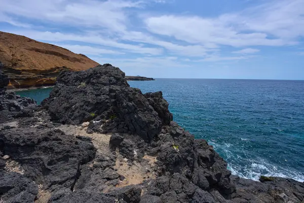 Tenerife 'deki Playa de Montana Amarilla yakınlarında volkanik kıyı şeridi ve okyanus dalgaları çarpışıyor. 