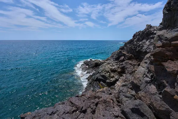 Tenerife 'deki Playa de Montana Amarilla yakınlarında volkanik kıyı şeridi ve okyanus dalgaları çarpışıyor. 