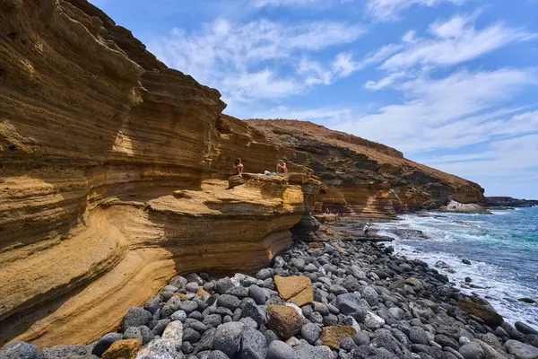 İspanya, Kanarya Adaları, Tenerife - 6 Mayıs 2025: İnsanlar Tenerife 'deki Playa de Montana Amarilla' da volkanik kayalıkların yakınında güneşleniyor ve yüzüyorlar