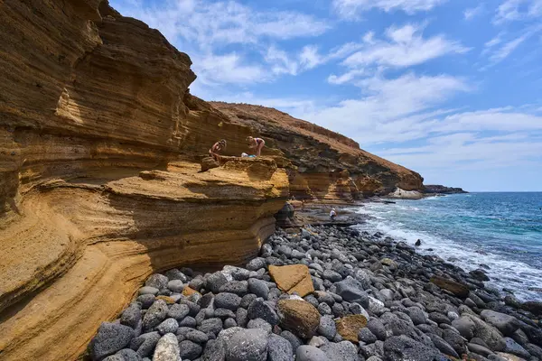 İspanya, Kanarya Adaları, Tenerife - 6 Mayıs 2025: İnsanlar Tenerife 'deki Playa de Montana Amarilla' da volkanik kayalıkların yakınında güneşleniyor ve yüzüyorlar