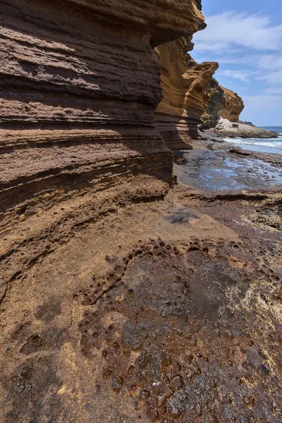 Tenerife 'deki Playa de Montana Amarilla' da okyanusun üzerindeki volkanik kayalıklar.