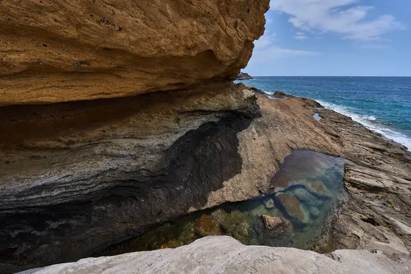 Tenerife 'deki Playa de Montana Amarilla' da okyanusun üzerindeki volkanik kayalıklar.