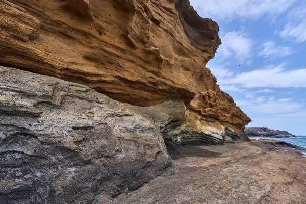 Tenerife 'deki Playa de Montana Amarilla' da okyanusun üzerindeki volkanik kayalıklar.