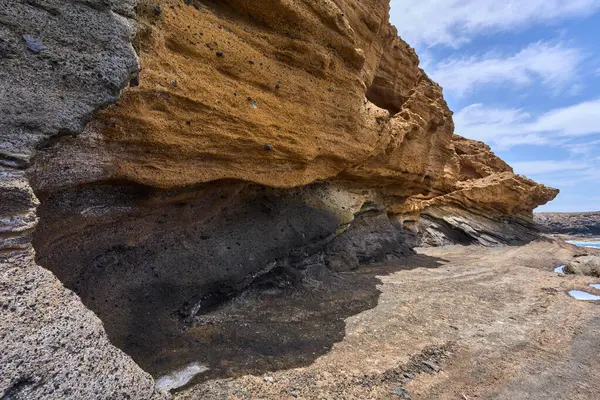 Tenerife 'deki Playa de Montana Amarilla' da okyanusun üzerindeki volkanik kayalıklar.