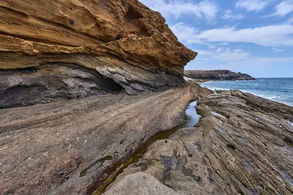 Tenerife 'deki Playa de Montana Amarilla' da okyanusun üzerindeki volkanik kayalıklar.