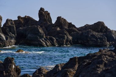 Volkanik kaya oluşumları Tenerife kıyısındaki La Vaca yakınlarındaki Charco El Diablo 'da denizden yükseliyor.