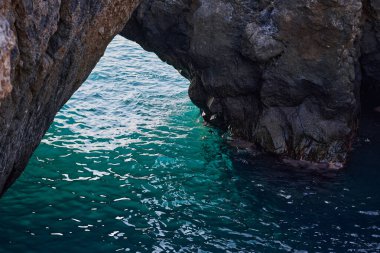Charco la Vaca 'da volkanik kaya kemeri. Açılıştan görülebilen canlı turkuaz deniz.
