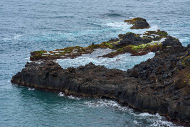 Tenerife 'deki El Bollullo plajı yakınlarındaki volkanik kaya oluşumları ve okyanus dalgalarının hava manzarası köpüklü dalgaların siyah kayalara ve yosun taşlarına çarpmasıyla