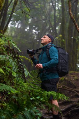 Sırt çantalı ve kameralı doğa fotoğrafçısı Tenerife 'deki Anaga ormanında yürüyüş ve çekim yapıyor.
