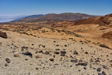 Volkanik yamaç kayalar ve dağınık çalılarla Caldera zeminine doğru iniyor.