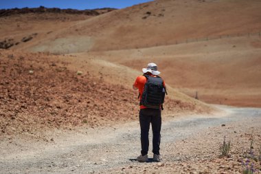 Sırt çantalı fotoğrafçı Teide 'a doğru Montana Blanca yürüyüş yolunda fotoğraf çekiyor.
