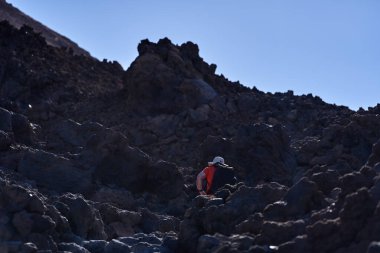 Piko del Teide 'nin zirvesine tırmanan adam volkanik oluşumlarla çevrili.