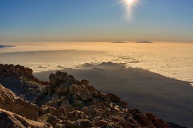 Pico del Teide krater kenarına bakan orman Corona Ormanı ve bulut versiyonu gün batımında ufukta görünen La Palma adası ile