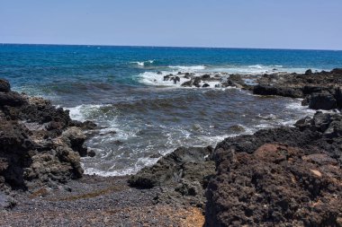 Dalgalar Tenerife Adası 'ndaki Malpais de Guimar kıyısı boyunca volkanik kayalara çarpıyor.