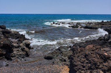 Dalgalar Tenerife Adası 'ndaki Malpais de Guimar kıyısı boyunca volkanik kayalara çarpıyor.