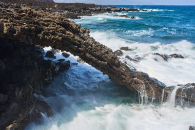 Volkanik deniz kemeri. Dalgalar çarpıyor ve su Tenerife kıyılarında akıyor.