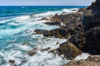 Dalgalar Tenerife Adası 'ndaki Malpais de Guimar kıyısı boyunca volkanik kayalara çarpıyor.