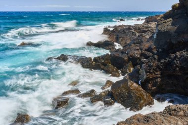Dalgalar Tenerife Adası 'ndaki Malpais de Guimar kıyısı boyunca volkanik kayalara çarpıyor.