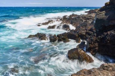 Dalgalar Tenerife Adası 'ndaki Malpais de Guimar kıyısı boyunca volkanik kayalara çarpıyor.