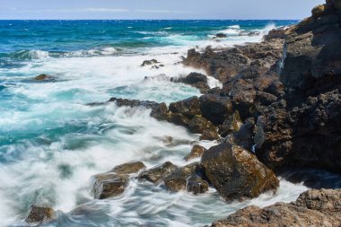 Dalgalar Tenerife Adası 'ndaki Malpais de Guimar kıyısı boyunca volkanik kayalara çarpıyor.