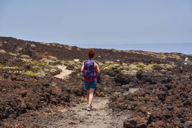 Tenerife Adası 'ndaki Malpais de Guimar' da volkanik bir patikada tek başına yürüyen bir kadın.