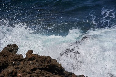 Dalgalar Tenerife Adası 'ndaki Malpais de Guimar kıyısı boyunca volkanik kayalara çarpıyor.