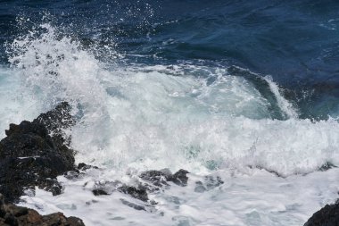 Dalgalar Tenerife Adası 'ndaki Malpais de Guimar kıyısı boyunca volkanik kayalara çarpıyor.