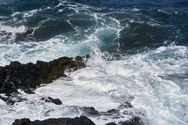 Dalgalar Tenerife Adası 'ndaki Malpais de Guimar kıyısı boyunca volkanik kayalara çarpıyor.