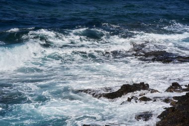 Dalgalar Tenerife Adası 'ndaki Malpais de Guimar kıyısı boyunca volkanik kayalara çarpıyor.