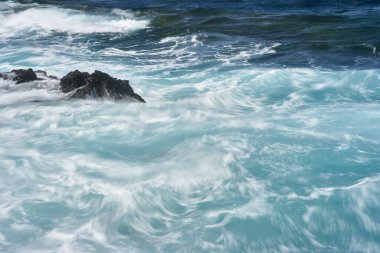 Dalgalar Tenerife Adası 'ndaki Malpais de Guimar kıyısı boyunca volkanik kayalara çarpıyor.