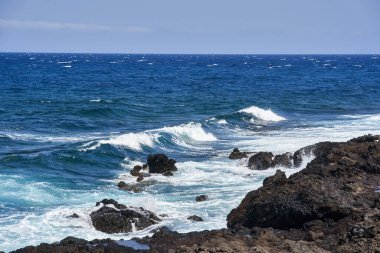 Dalgalar Tenerife Adası 'ndaki Malpais de Guimar kıyısı boyunca volkanik kayalara çarpıyor.