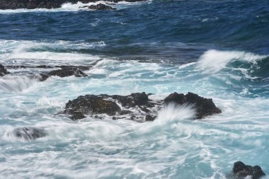 Dalgalar Tenerife Adası 'ndaki Malpais de Guimar kıyısı boyunca volkanik kayalara çarpıyor.