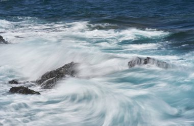 Dalgalar Tenerife Adası 'ndaki Malpais de Guimar kıyısı boyunca volkanik kayalara çarpıyor.