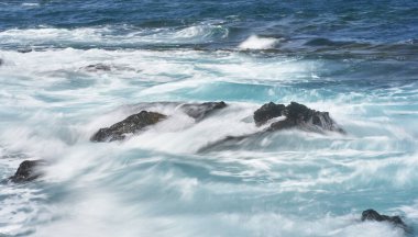 Dalgalar Tenerife Adası 'ndaki Malpais de Guimar kıyısı boyunca volkanik kayalara çarpıyor.