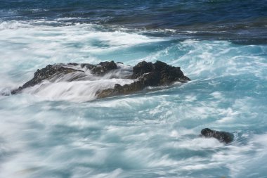 Dalgalar Tenerife Adası 'ndaki Malpais de Guimar kıyısı boyunca volkanik kayalara çarpıyor.