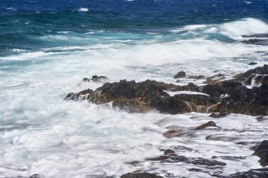 Dalgalar Tenerife Adası 'ndaki Malpais de Guimar kıyısı boyunca volkanik kayalara çarpıyor.