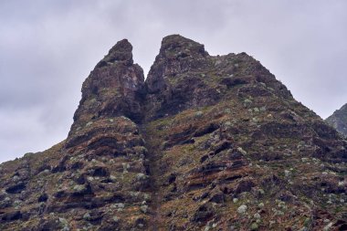 Anaga, Tenerife 'deki Roque Dos Hermanos' un volkanik kaya oluşumu dağınık bitki örtüsüyle kaplanmış gökyüzü altında
