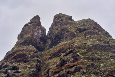 Anaga, Tenerife 'deki Roque Dos Hermanos' un volkanik kaya oluşumu dağınık bitki örtüsüyle kaplanmış gökyüzü altında