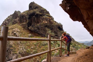 Sırt çantalı bir kadın Tenerife 'deki yürüyüş parkurundan volkanik kayalıkları fotoğraflıyor.
