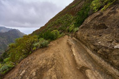 Anaga Tenerife 'deki aşınmış uçurumun aşağısında dönen volkanik yol daralıyor.