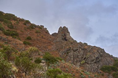 Tenerife 'nin uzak Teno bölgesinde berrak mavi bir gökyüzünün altında sivri bir volkanik zirvenin etrafında dönen dar dağ yolu.