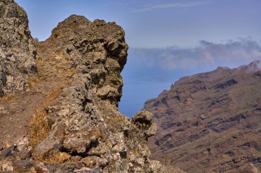 Atlantik kıyısındaki Teno dağlarındaki kahverengi kayalık yamaçların ve bitkilerin geniş manzarası