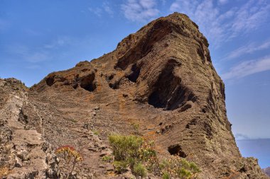 Tenerife 'nin Teno dağlarında mavi bir gökyüzünün altında sarp kayalıklara tırmanan patika.