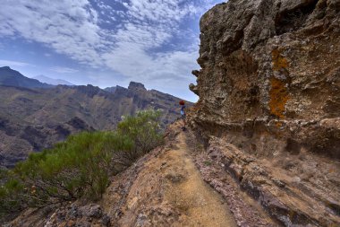 Yürüyüşçü, Tenerife 'nin Teno dağlarındaki sünger taşlarının yanında dar bir patikada duruyor.