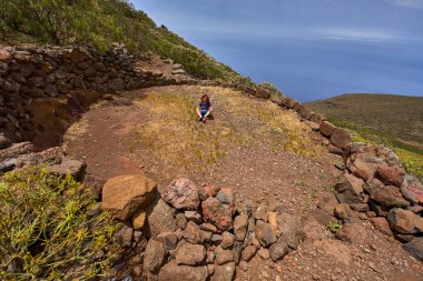 Tenerife 'de okyanusun üzerindeki tarihi dairesel harman döşemesinde oturan kadın.