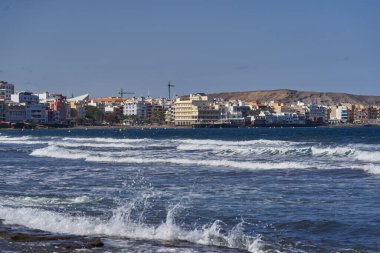 İspanya, Kanarya Adaları, Tenerife, Playa del Medano - 05 Haziran 2025: El Medano kasabası dalgalar ve renkli deniz manzaralı binalarla okyanustan görüldü