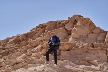 Bir fotoğrafçı aşınmış tuff kayası oluşumlarını yakalamak için Los Derriscaderos 'ta dik bir yamaca tırmanıyor.