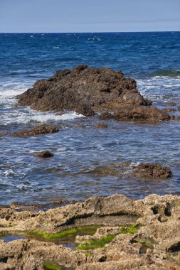 Playa del Medano 'da deniz yosunlu volkanik kıyı kayaları yaklaşan okyanus dalgaları altında