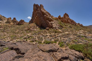 Kurak volkanik arazide, güneşli bir gökyüzünün altında, Roques de Garcia 'nın kaya oluşumlarına doğru yürüyüş izleri.